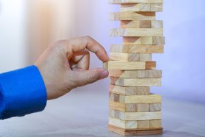 a close up of a hand removing a wooden block from a tower made up of wooden blocks.