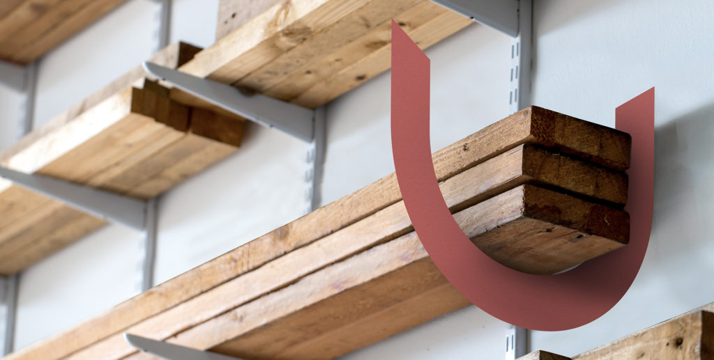 Wooden shelves on a wall with a red curved decorative element in front.