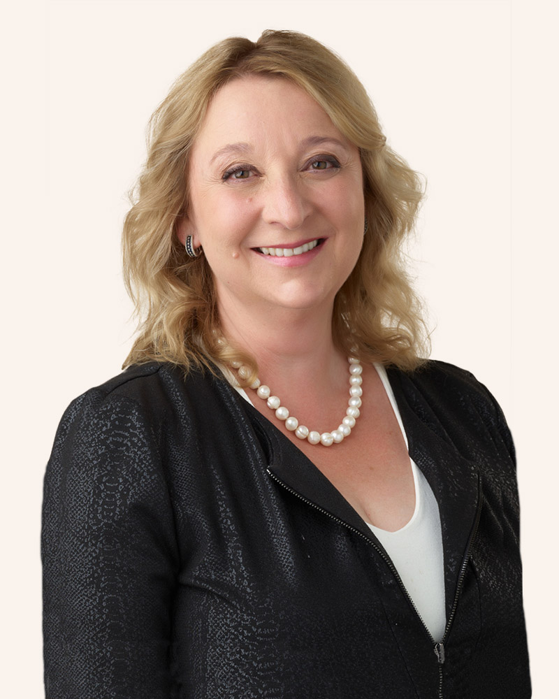 A smiling woman in business attire over a light background.