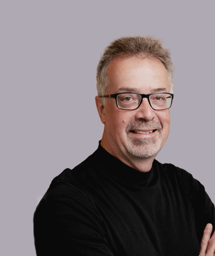 A smiling man with glasses over a light background.