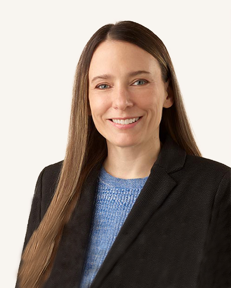 A smiling woman in business attire over a light background.