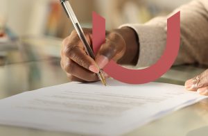 A person signing a document on a glass-topped table with a pen. The image features a large, red curved shape overlaying the hand and document.